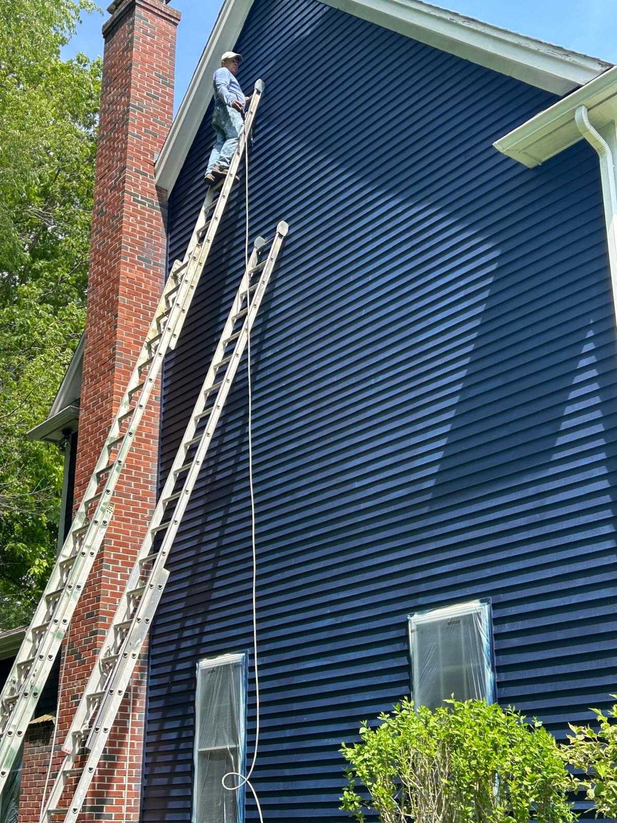 Creative Painting crew on a ladder painting a Massachusetts home navy blue